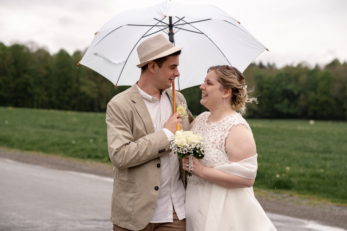les mariés sous la pluie avec des parapluies